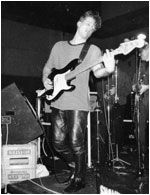 BASH OUT THE ODD live October, 1989 at The Bull & Gate in  Kentish Town, London. Mark Mortimer with, in the background, the brass section, Bryan Hurdley (left, rear), Mark Allison (right, rear).  Not pictured was Martin Cooper.